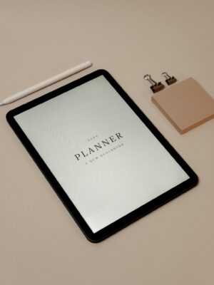 2024 digital planner displayed on a tablet with minimalistic accessories and pink background.