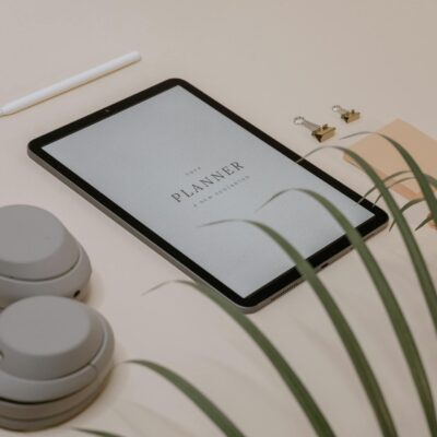 A flat lay of a minimalist desk setup featuring a tablet displaying a planner for new resolutions.