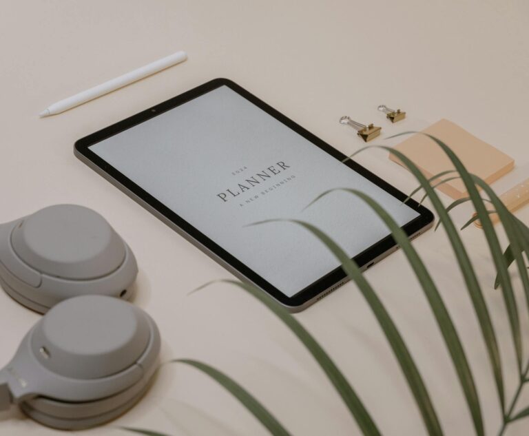 A flat lay of a minimalist desk setup featuring a tablet displaying a planner for new resolutions.