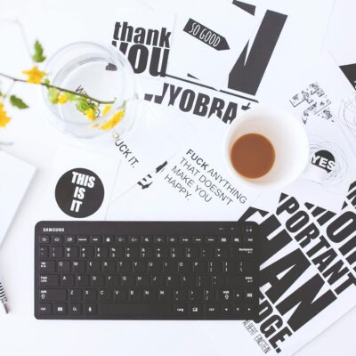 Overhead view of a creative workspace with scattered papers, coffee cup, and keyboard.