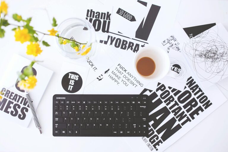 Overhead view of a creative workspace with scattered papers, coffee cup, and keyboard.